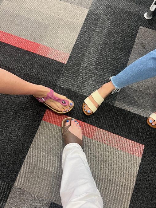 ShHot of 3 people's feet, all wearing a different shade of blue nail varnish