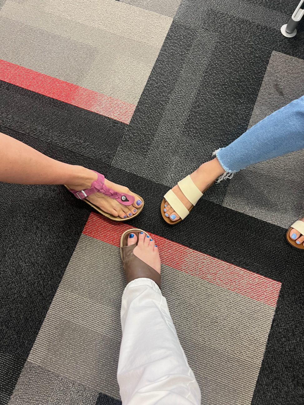 ShHot of 3 people's feet, all wearing a different shade of blue nail varnish